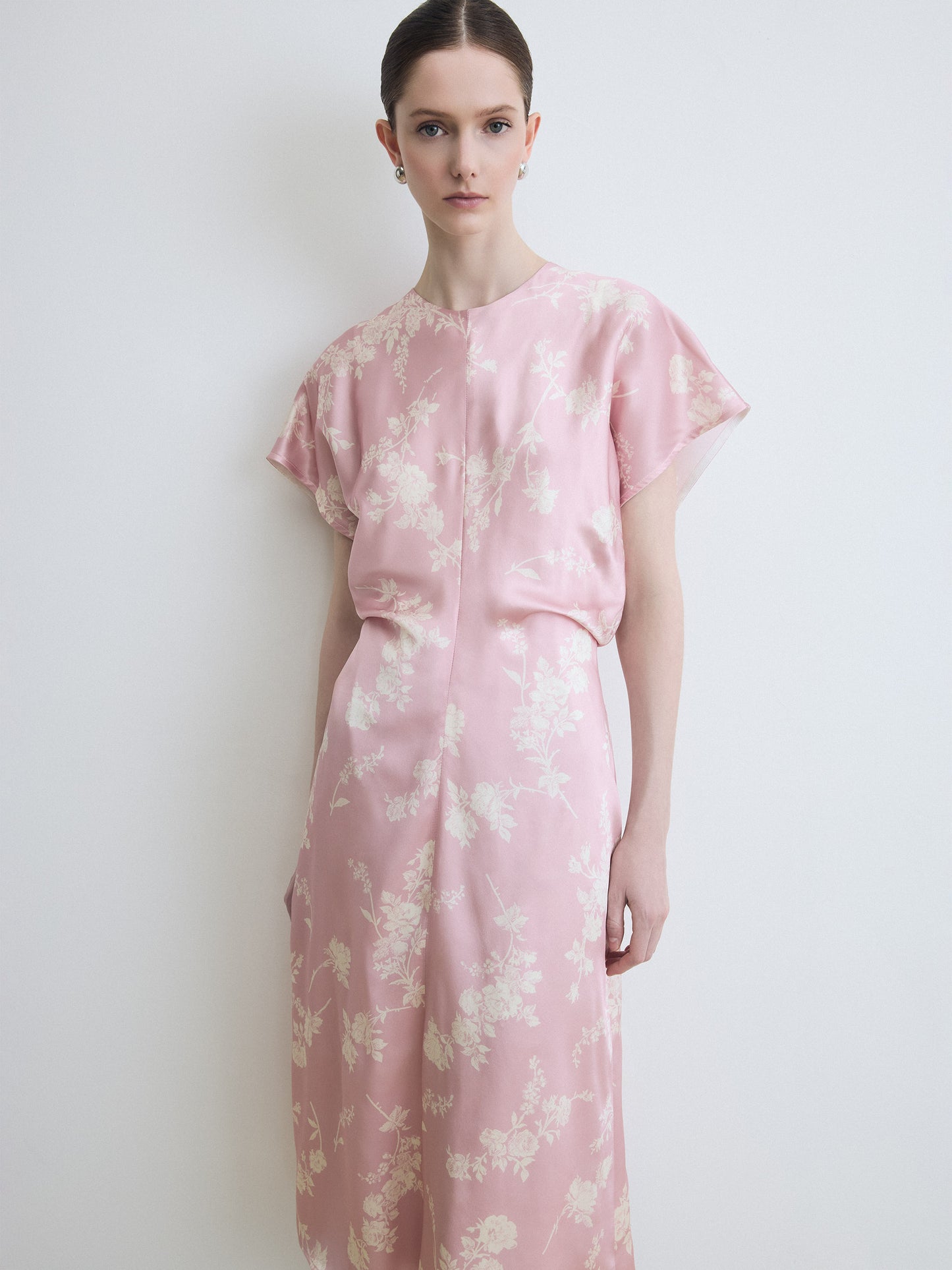 Woman wearing a pink floral dress against a white background