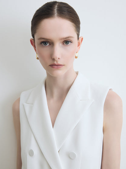 Woman wearing a white sleeveless blazer against a plain background