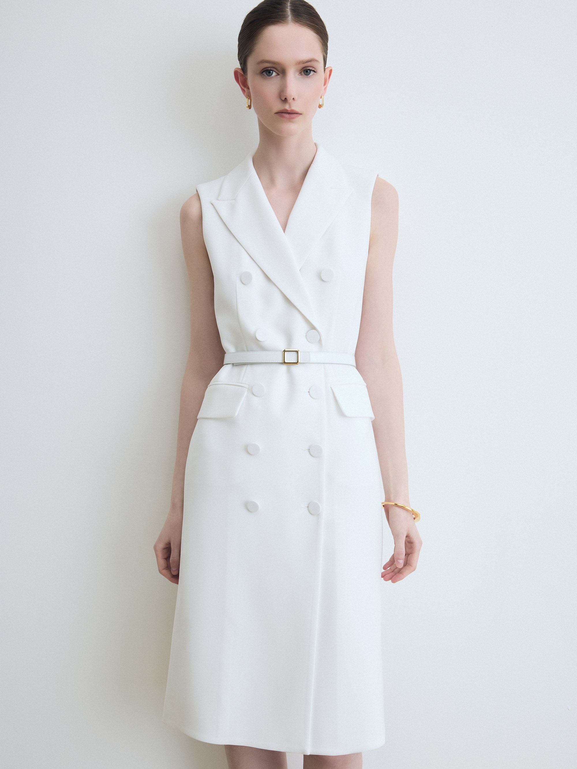 Woman wearing a white sleeveless dress against a plain background