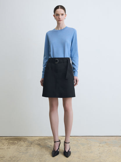 Woman wearing a blue sweater and black skirt against a white background