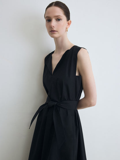 Woman wearing a black sleeveless dress against a plain background