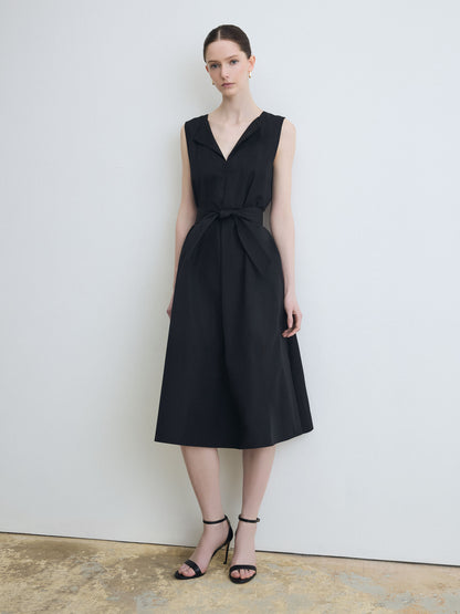 Woman wearing a black sleeveless dress against a plain background