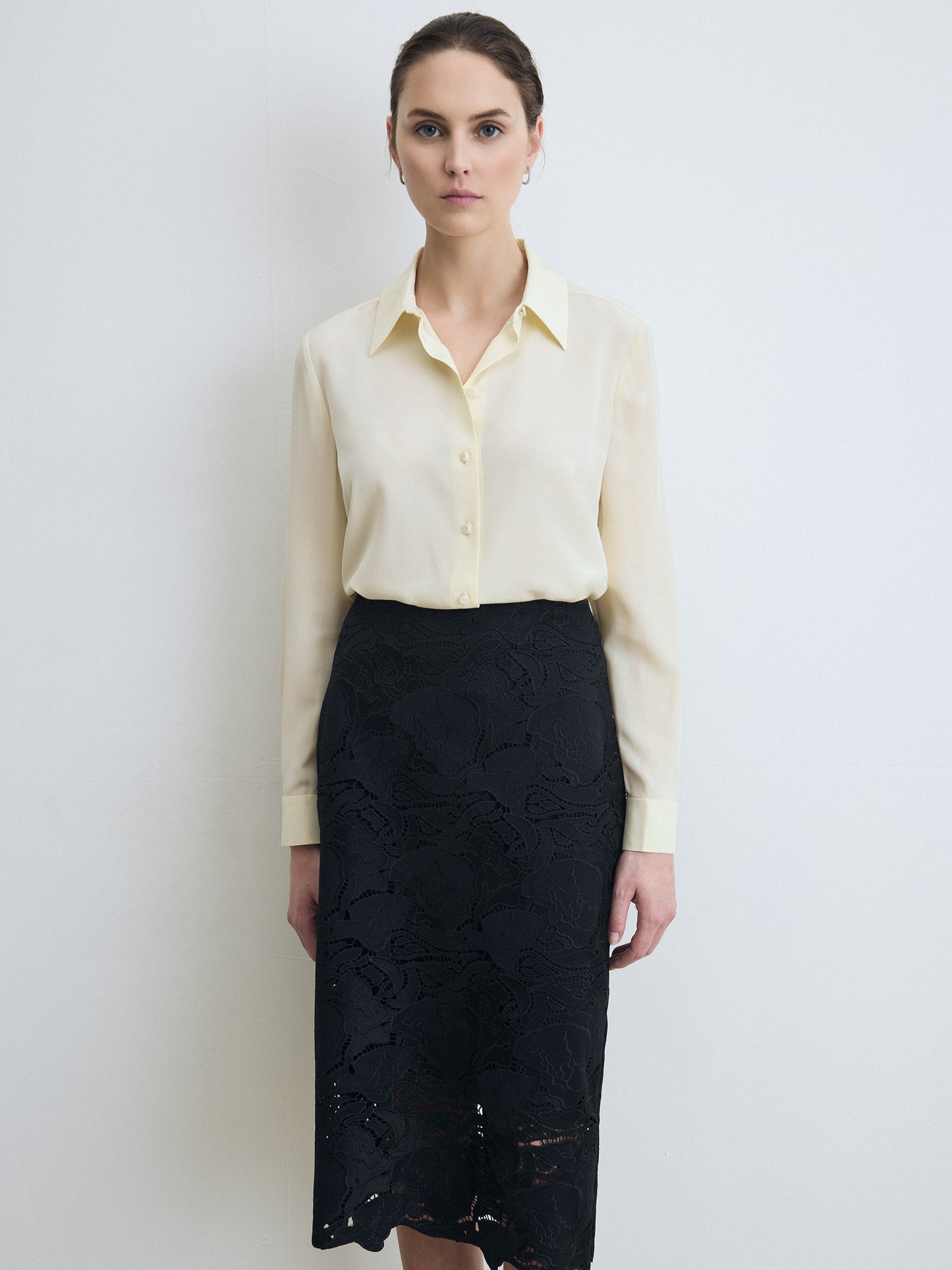 Woman wearing a lemonade blouse and black lace skirt against a white background
