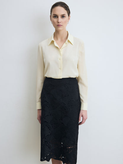 Woman wearing a lemonade blouse and black lace skirt against a white background