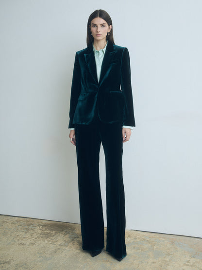 Woman wearing a dark green velvet suit by Judith and Charles against a white background