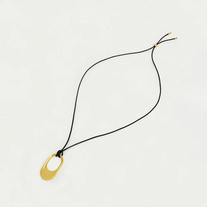 Necklace with a gold pendant on a black cord against a light gray background