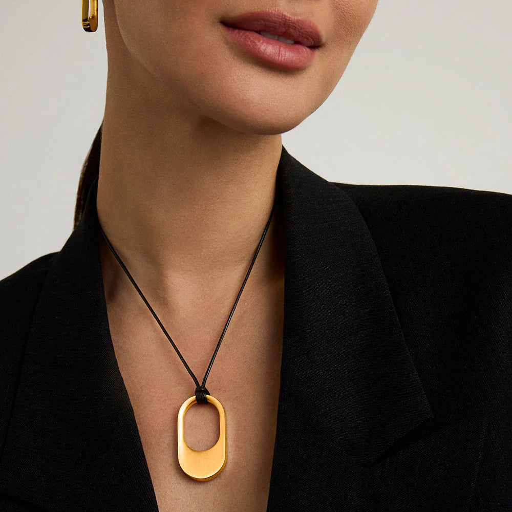 Gold necklace with a pendant worn by a person against a neutral background