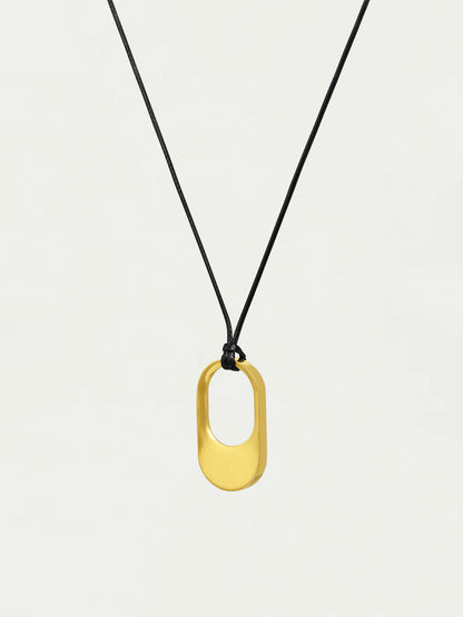 Gold pendant necklace on a black cord against a white background
