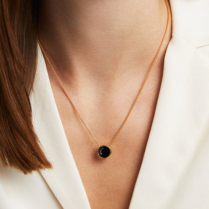 Woman wearing the Signature Knockout Pendant features a multi-faceted, brilliant-cut gemstone suspended on a fluid, adjustable box chain.