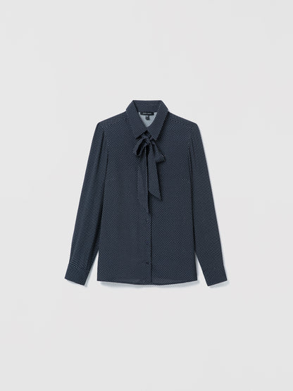 Navy off white patterned blouse with a tie detail on a light gray background