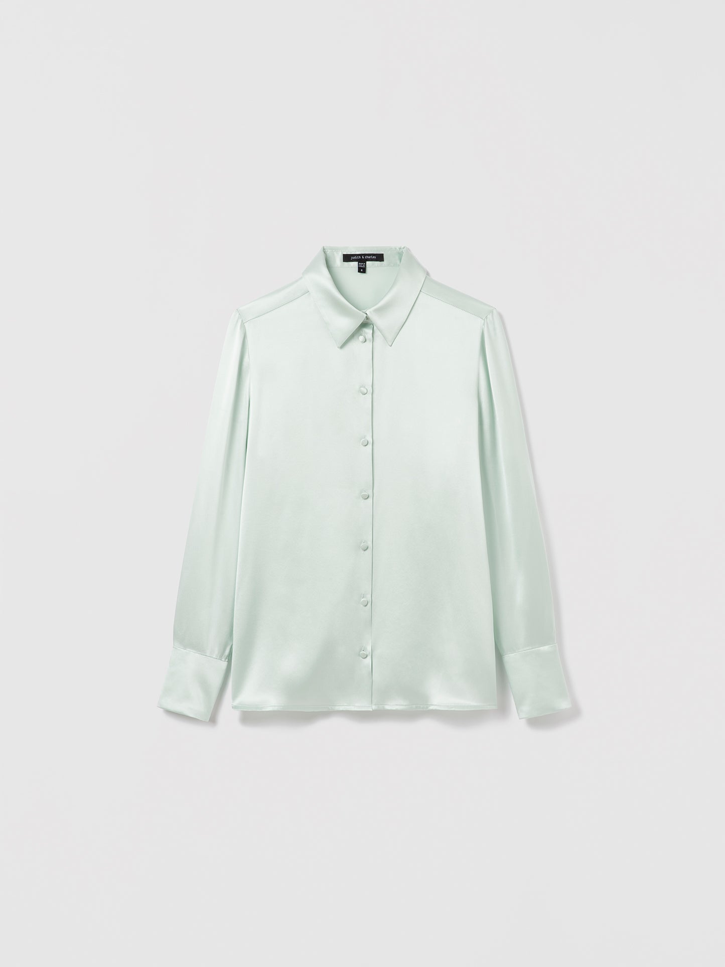 Light Sage satin silk blouse by Judith & Charles featuring long sleeves, a shirt collar, and front button closure; semi-fitted silhouette, unlined, 25″ back length.