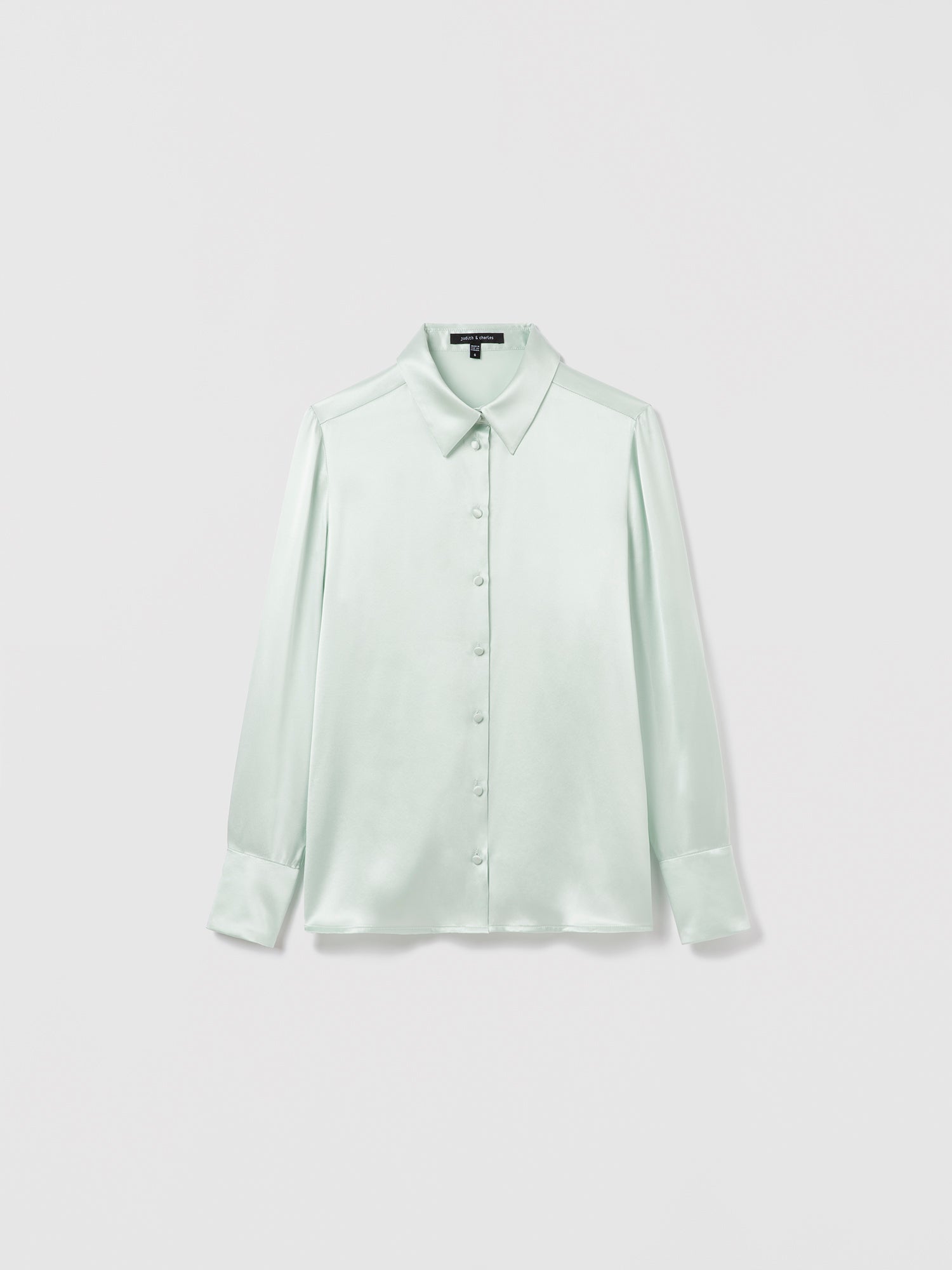 Light Sage satin silk blouse by Judith & Charles featuring long sleeves, a shirt collar, and front button closure; semi-fitted silhouette, unlined, 25″ back length.