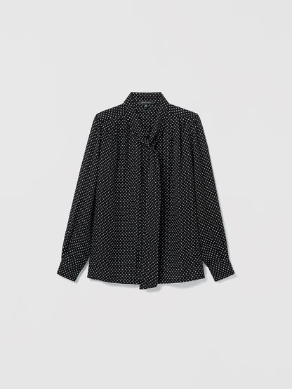 Flat lay of black and white silk blouse with long sleeves, pleats, and neck tie. Straight fit, unlined, with button closure 